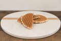 Three wafers on a round marble cutting board with a wooden edge.