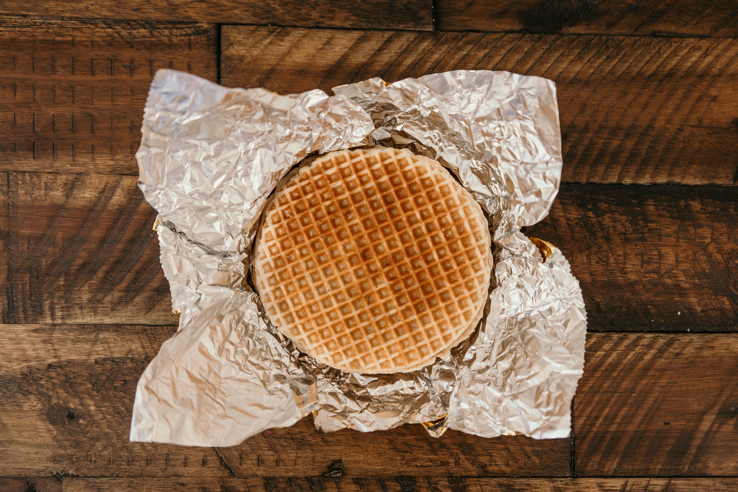 Waffle on crumpled golden wrapping paper on a wooden surface
