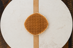 Waffle on a round marble cutting board with a wooden stripe on a wooden surface