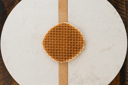 Waffle on a round marble cutting board with a wooden stripe on a wooden surface