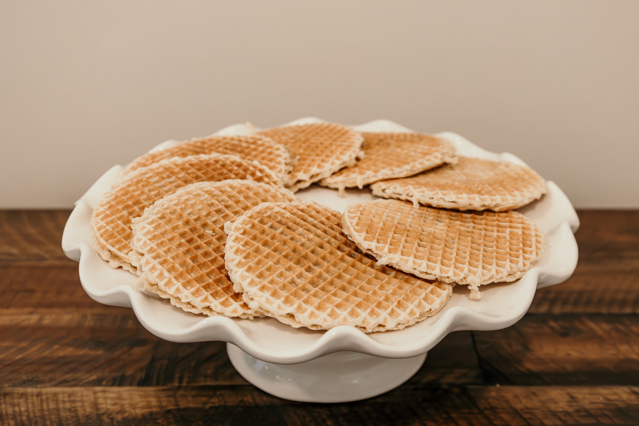 Stack of waffles on a white plate with a wooden background