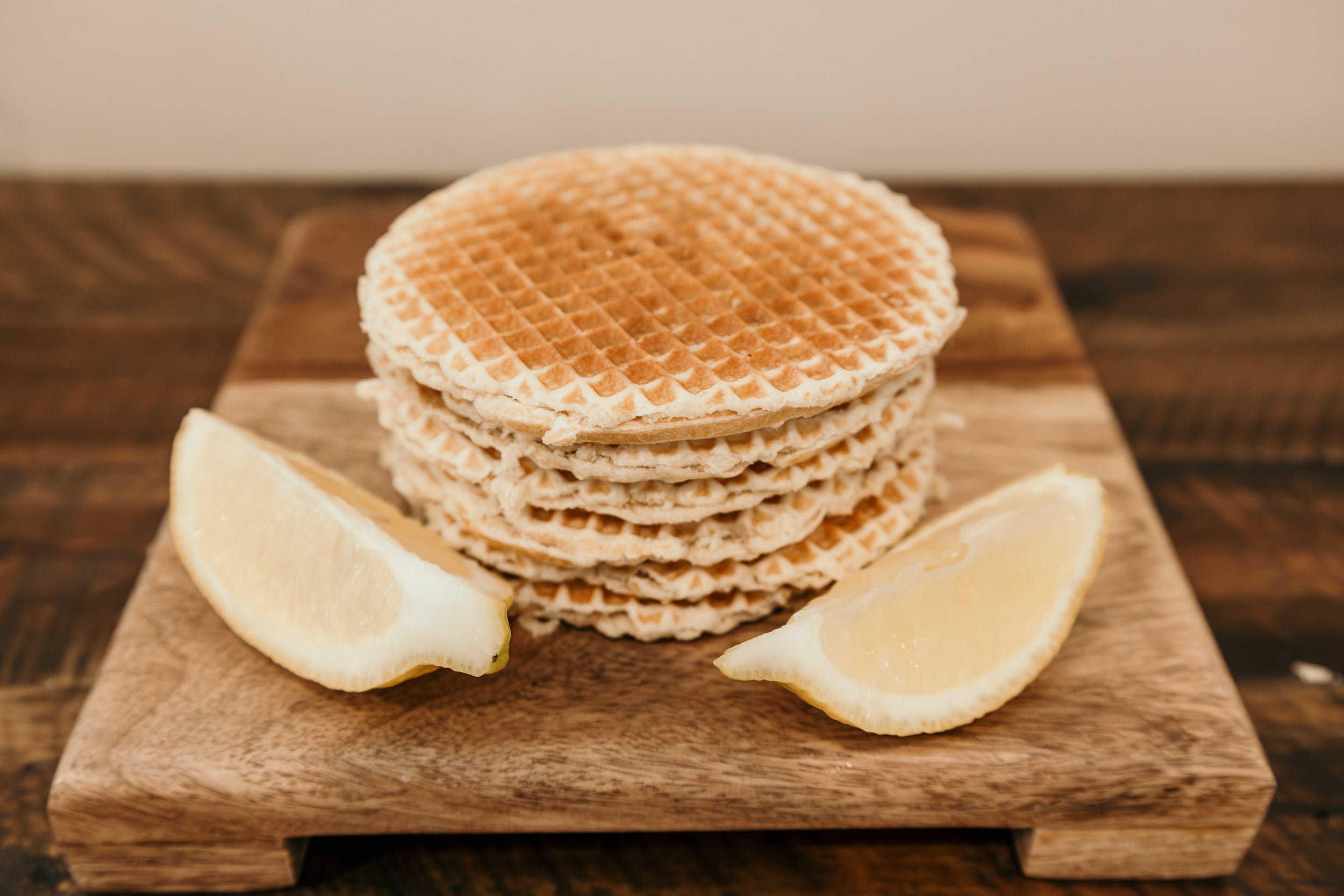 Stack of waffles on a wooden board with lemon wedges