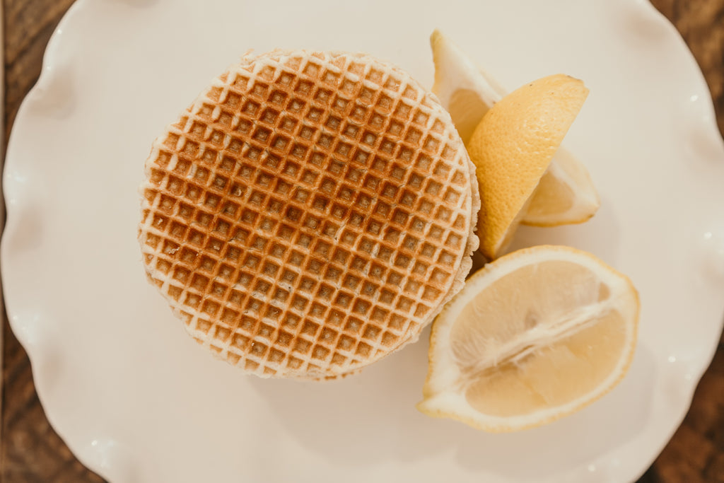 Waffle on a white plate with lemon wedges